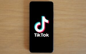 Smartphone with TikTok app displayed on black screen against a wooden background.